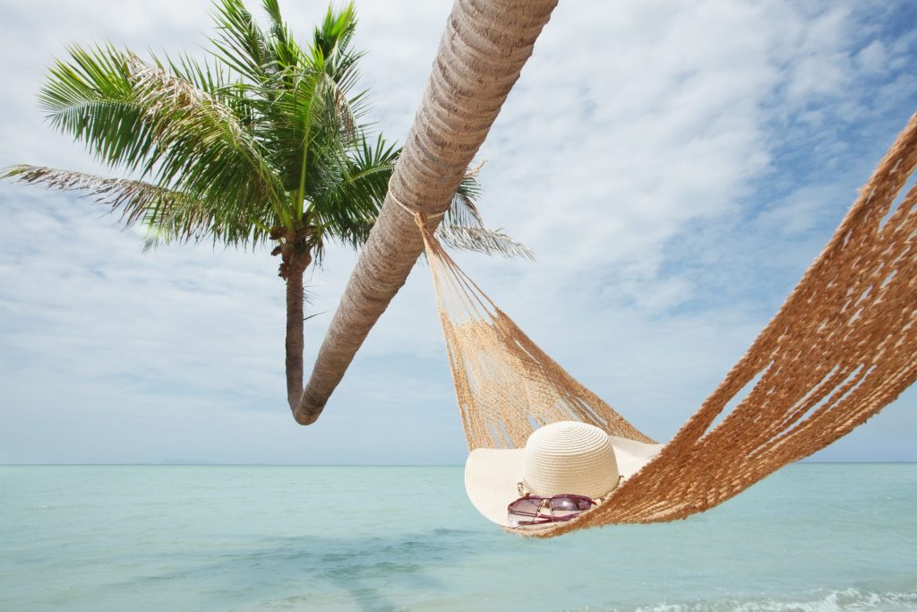 wakacje pod palmą nad morzem i hamak na którym leży kapelusz