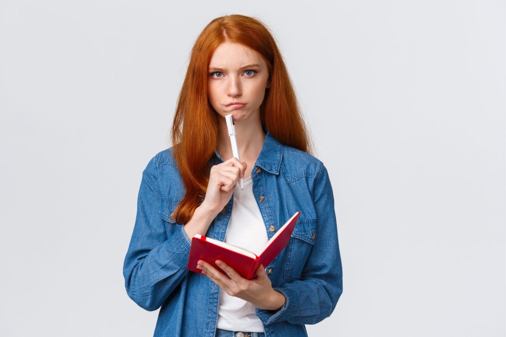 girl holds notebook and pen and thinks