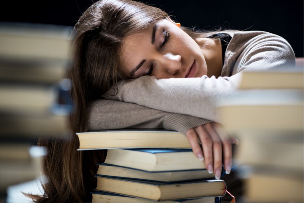 dziewczyna w brązowych włosach śpi na książkach