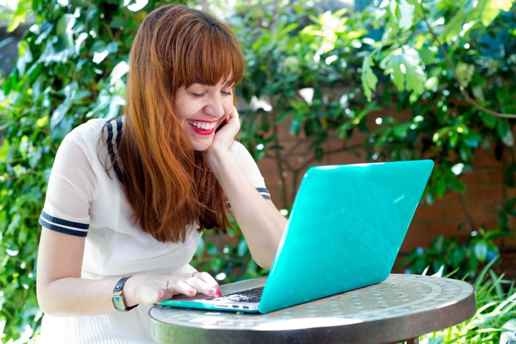 śmiejąca się kobieta przed laptopem 