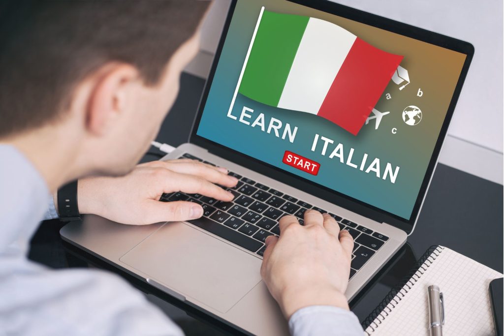 mężczyzna trzymający dłonie na laptopie, na którym włączony jest kurs języka włoskiego 
