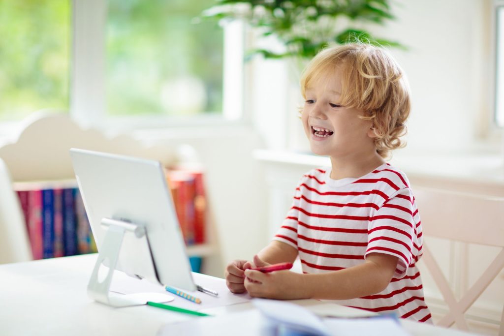 uśmiechnięty chłopiec patrzący na monitor komputera