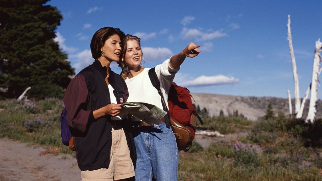 dos mujeres con un mapa en la mano, mirando hacia un lado