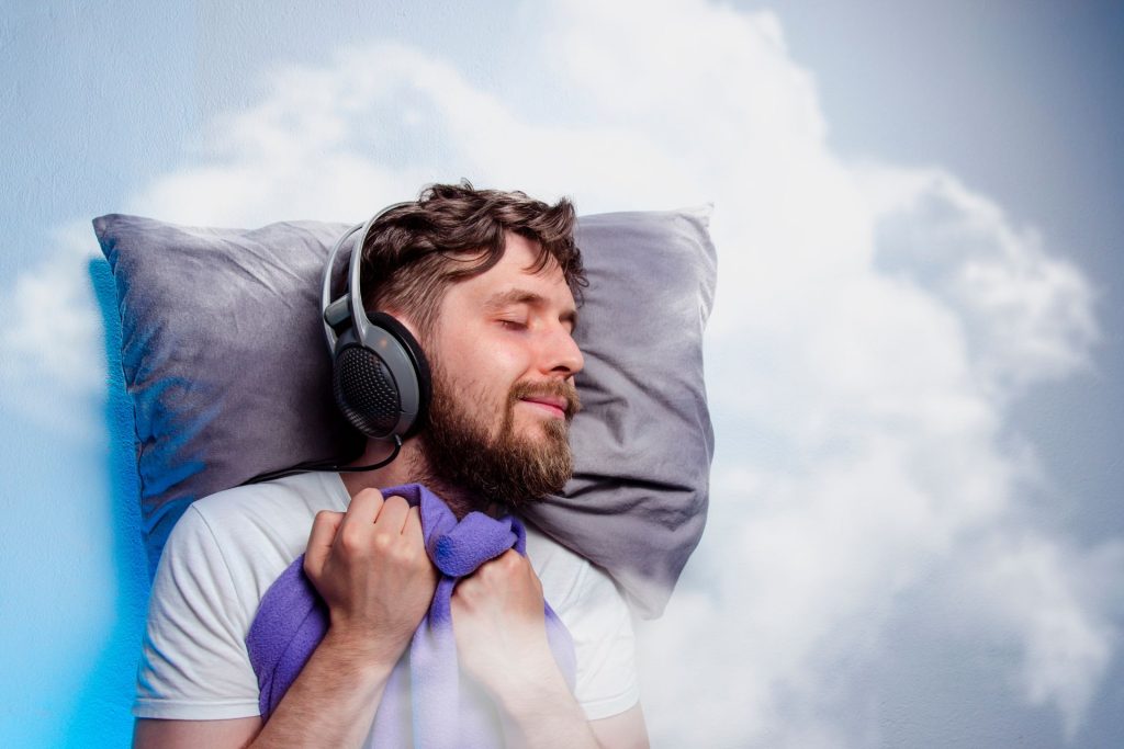 lächelnder, schlafender Mann mit Kopfhörern auf den Ohren